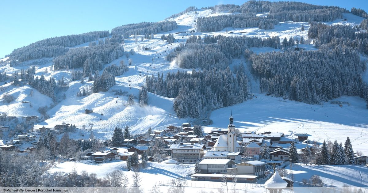 The village of Jochberg in the snow, with the church and the ski slopes behind it