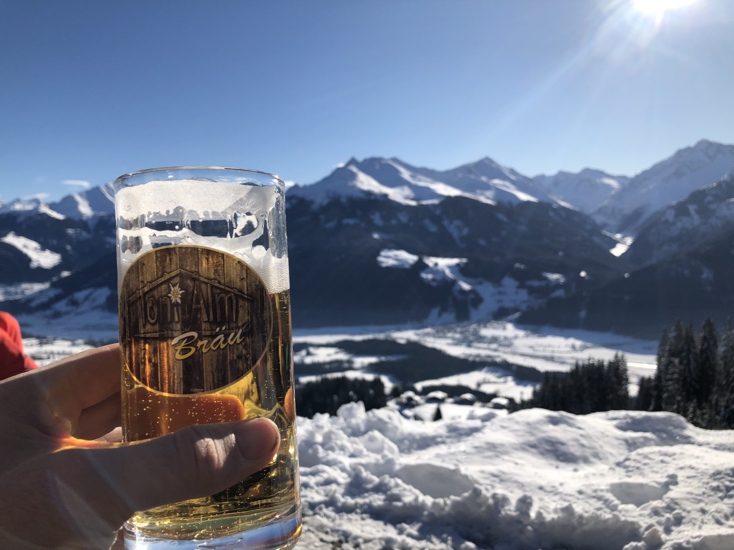 Een glas bier in de zon, met uitzicht over het winterse dal bij Jochberg